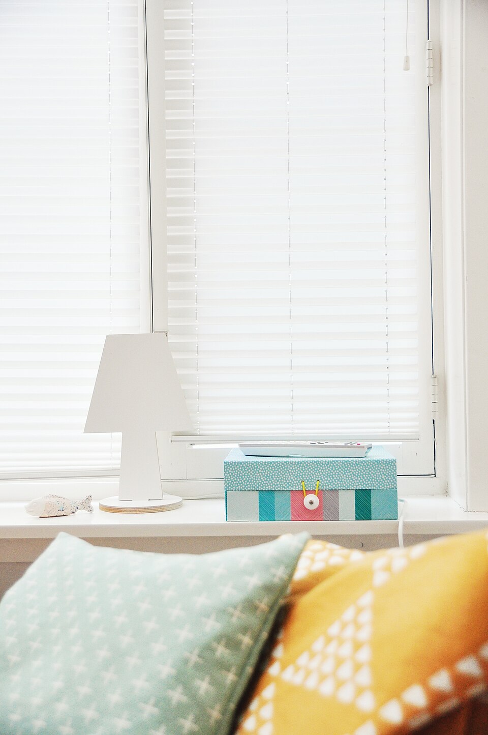 Cushions and a bedside windowsill in soft daylight